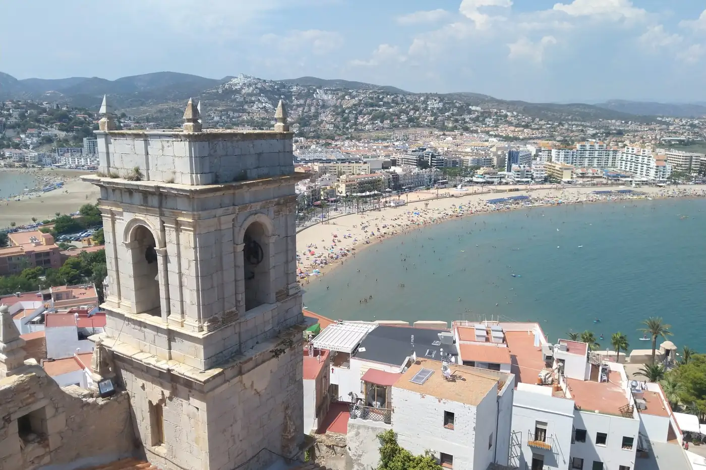 Bell tower above a curving beach and white town