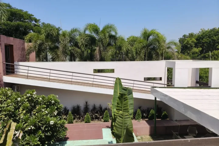 White modern home with a sloped terrace ramp framed by palms