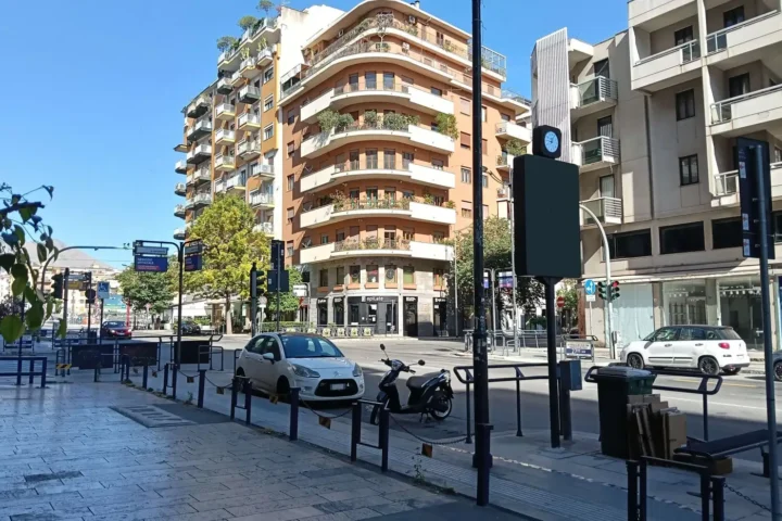 Modern apartment block with curved balconies on a tree-lined street