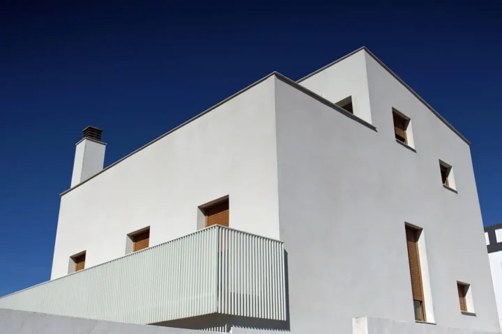 Minimal white house with a deep blue sky and slim balcony