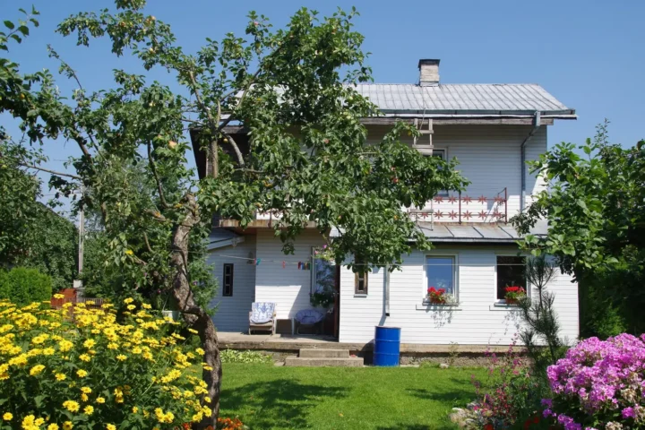 White two-storey house behind a flowering garden