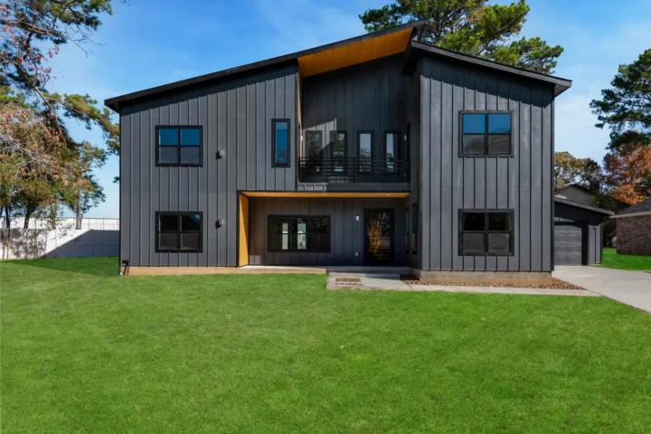 Two-storey dark-clad modern home with large windows and a broad lawn
